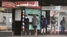 Para pria antre untuk memotong rambut di luar barber shop di Melbourne, Australia, Senin (19/10/2020). Warga Kota Melbourne, pada Senin (19/10), akhirnya bisa bernafas lega saat sejumlah pembatasan dilonggarkan setelah lockdown tahap keempat yang ketat selama sekitar 100 hari. (William WEST/AFP)