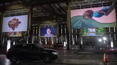 Orang-orang mengunjungi pameran seni dengan mengendarai mobil mereka melintasi gudang yang memajang lukisan dan foto di Sao Paulo pada 30 Juli 2020. Dengan galeri-galeri dan museum ditutup akibat pandemi virus corona, pemilik galeri seni Brasil meresmikan pameran drive-thru. (NELSON ALMEIDA/AFP)
