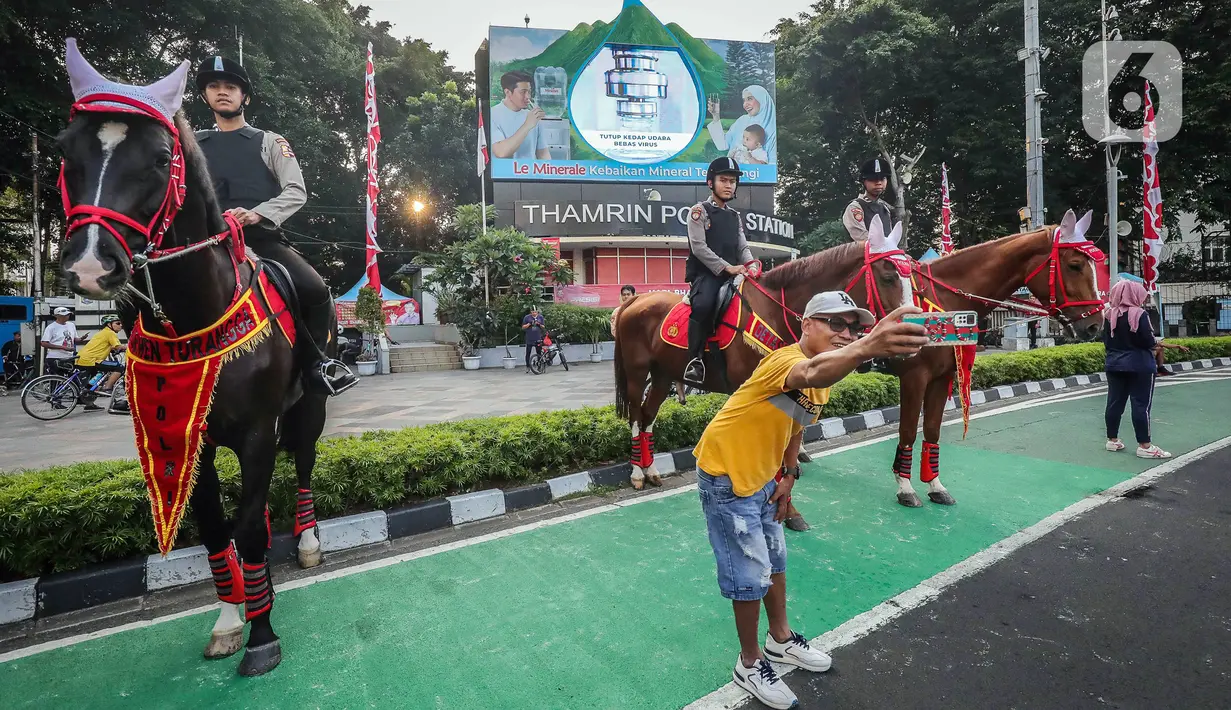 <p>Warga berswafoto dengan polisi berkuda yang bersiaga saat hari bebas kendaraan bermotor (HBKB) atau car free day (CFD) di kawasan Bundaran HI, Jakarta, Minggu (23/7/2023). Selain bagian dari pengamanan, kehadiran polisi berkuda ini juga menjadi sarana wisata yang menghibur warga saat beraktivitas di CFD. (Liputan6.com/Faizal Fanani)</p>