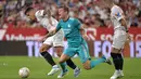 Gelandang Real Madrid Toni Kroos (tengah) terjatuh saat melawan Sevilla pada lanjutan Liga Spanyol di stadion Ramon Sanchez Pizjuan, Senin (18/4/2022) dini hari WIB. Real Madrid sukses menaklukkan Sevilla 3-2. (CRISTINA QUICLER / AFP)