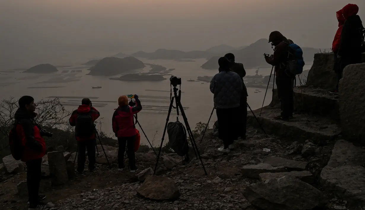 Wisatawan menunggu matahari terbit di Desa Hua Zhu, Xiapu, Provinsi Fujian, China, Kamis (12/12/2019). Xiapu menjadi daya tarik tersendiri bagi fotografer pemula karena jauh dari gedung pencakar langit dan hiruk pikuk kota-kota besar di China. (RETAMAL HECTOR/AFP)