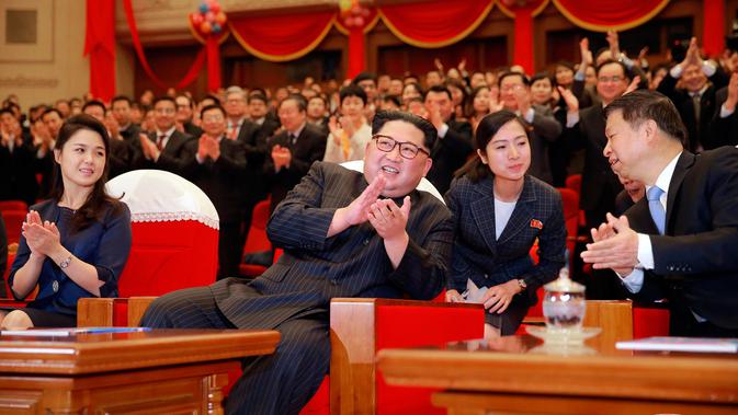 Pemimpin Korea Utara Kim Jong-Un didampingi istrinya Ri Sol Ju (kanan) bertepuk tangan saat menonton penampilan kelompok seni dari China di Pyongyang, Korea Utara (17/4). (Korean Central News Agency/Korea News Service via AP)