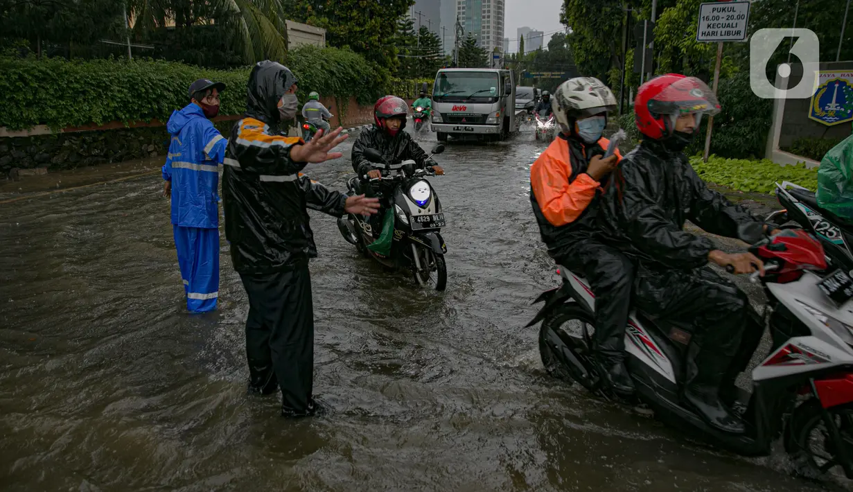 Petugas mengatur kelancaran lalu lintas saat air menggenangi ruas Jalan Gatot Subroto, Jakarta, Kamis (18/2/2021). Hujan deras yang mengguyur wilayah Jakarta menyebabkan terjadinya genangan di beberapa ruas jalan, meski begitu sejauh ini kendaraan masih dapat melintas. (Liputan6.com/Faizal Fanani)