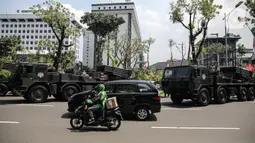 Pengendara melintas saat sejumlah kendaraan alat utama sistem senjata (alutsista) TNI berjajar di kawasan Istana Merdeka, Jakarta, Selasa (4/10/2022). Kegiatan ini dalam rangka HUT ke-77 TNI yang akan berlangsung di Istana Merdeka pada 5 Oktober besok. (Liputan6.com/Faizal Fanani)