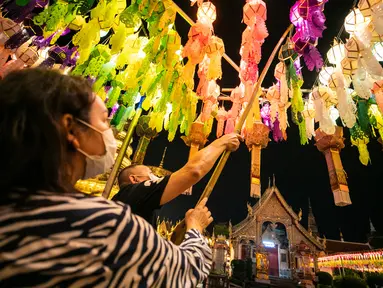 Orang-orang menggantung lampion di Wat Phra That Hariphunchai, Lamphun, Thailand, 1 November 2020. Sekitar 100.000 lampion digantung di Wat Phra That Hariphunchai sebagai bagian dari perayaan festival tradisional Yi Peng. (Xinhua/Zhang Keren)