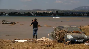 Penduduk lokal Christos Pavlou mengambil gambar mobilnya yang tenggelam setelah badai di desa Bourtzi di pulau Evia, Yunani, Senin (10/8/2020). Tujuh orang, termasuk dua lansia dan bayi berusia delapan bulan, tewas saat badai melanda pulau Evia pada Minggu kemarin. (AP Photo/Thanassis Stavrakis)