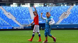 Maskot resmi Piala Eropa 2020, Skillzy dan pemain Rusia, Alexander Erokhin menyapa penonton saat presentasi di Stadion Saint Petersburg, Rusia (27/3). Kota Saint Petersburg akan menyelenggarakan empat pertandingan termasuk pertandingan perempat final selama UEFA Euro 2020. (AFP Photo/Olga Maltseva)