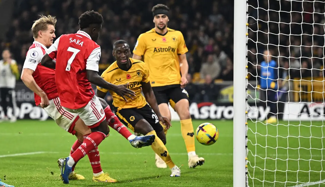 Pemain Arsenal Martin Odegaard (kiri) mencetak gol ke gawang Wolverhampton Wanderers pada pertandingan sepak bola Liga Inggris di Stadion Molineux, Wolverhampton, Inggris, 12 November 2022. Arsenal menang 2-0. (Oli SCARFF/AFP)