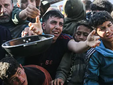 Warga Palestina yang mengungsi berebut untuk makanan di Khan Younis, selatan Jalur Gaza pada Jumat 6 Maret 2026. Krisis pangan di Gaza kembali mencapai titik kritis. Situasi ini imbas eskalasi konflik regional yang memicu penutupan seluruh pintu perlintasan perbatasan ke Gaza oleh Israel. (Bashar Taleb/AFP)