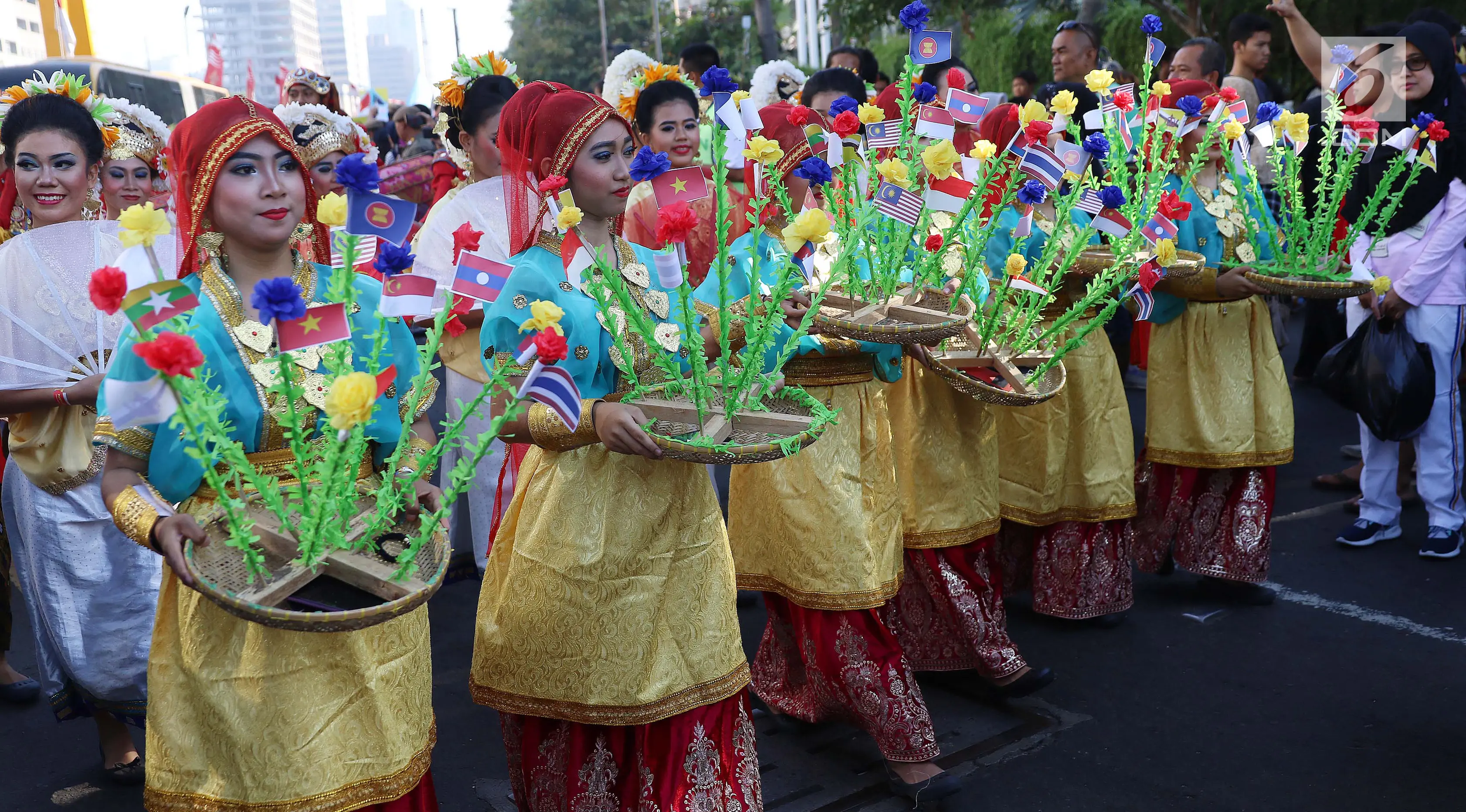 Peserta mengenakan baju adat membawa bendera negara anggota ASEAN saat parade ASEAN 50 Tahun di Jakarta, Minggu (27/8). Parade itu diikuti oleh seluruh negara yang tergabung dalam ASEAN. (Liputan6.com/Angga Yuniar)