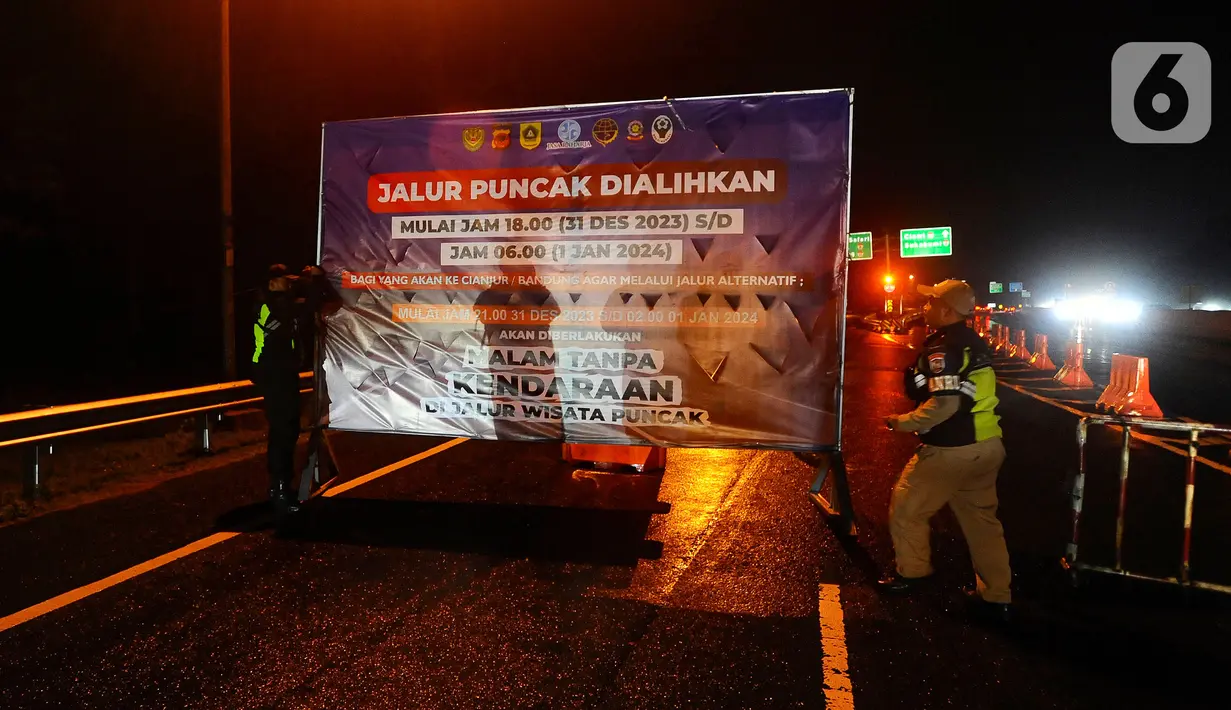 Petugas Tol Jasa Marga memasang papan penutupan jalur Puncak di pintu keluar tol Gadog, Bogor, Jawa Barat, Minggu (31/12/2023). (merdeka.com/Arie Basuki)