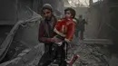 Seorang anak korban reruntuhan bangunan digendong pria untuk diselamatkan usai terjadi serangan udara dari pasukan Assad di wilayah Ghouta timur, Suriah (7/2). Dalam serangan ini dilaporkan sedikitnya, 47 warga sipil tewas. (AFP Photo/Hamza Al-Ajweh)