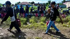 Warga membawa tabung gas di sebuah stasiun pengisian dan pembelian LPG setelah banjir bandang di Banda Aceh pada Rabu 17 Desember 2025. Kelangkaan gas masih terjadi di Kota Banda Aceh. (CHAIDEER MAHYUDDIN/AFP)
