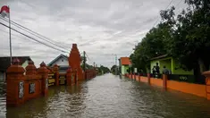 Sebuah jalan yang tergenang air akibat luapan sungai terlihat setelah hujan lebat di desa Tempuran, Mojokerto, Jawa Timur, pada 9 Desember 2024. (Juni KRISWANTO/AFP)