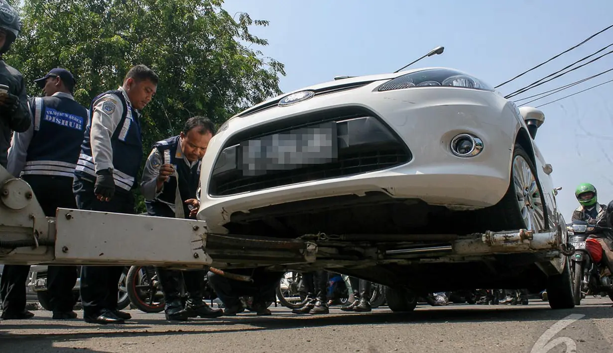 Petugas Dishub memastikan alat derek bekerja dengan baik untuk mengangkut mobil ini, Jakarta, Selasa (23/9/2014) (Liputan6.com/Faizal Fanani)