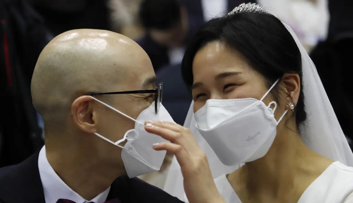 Pasangan memakai masker mengikuti kegiatan nikah massal di Cheong Shim Peace World Center di Gapyeong, Korea Selatan, Jumat, (7/2/2020). Meski memakai masker untuk mencegah virus corona, para pasangan pengantin tampak bahagia di acara tersebut. (AP Photo/Ahn Young-joon)