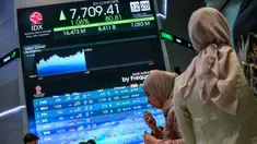 Orang-orang berdiri di samping layar yang menampilkan angka-angka perdagangan saham di gedung Bursa Efek Indonesia di Jakarta pada Rabu 10 September 2025. (BAY ISMOYO/AFP)