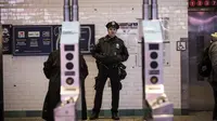 Petugas kepolisian New York berjaga di pintu masuk stasiun kereta bawah tanah Times Square saat jam sibuk malam di New York City, Senin (11/12). Sebelumnya ledakan bom terjadi di terminal bawah tanah kawasan Manhattan. (Drew Angerer/Getty Images/AFP)