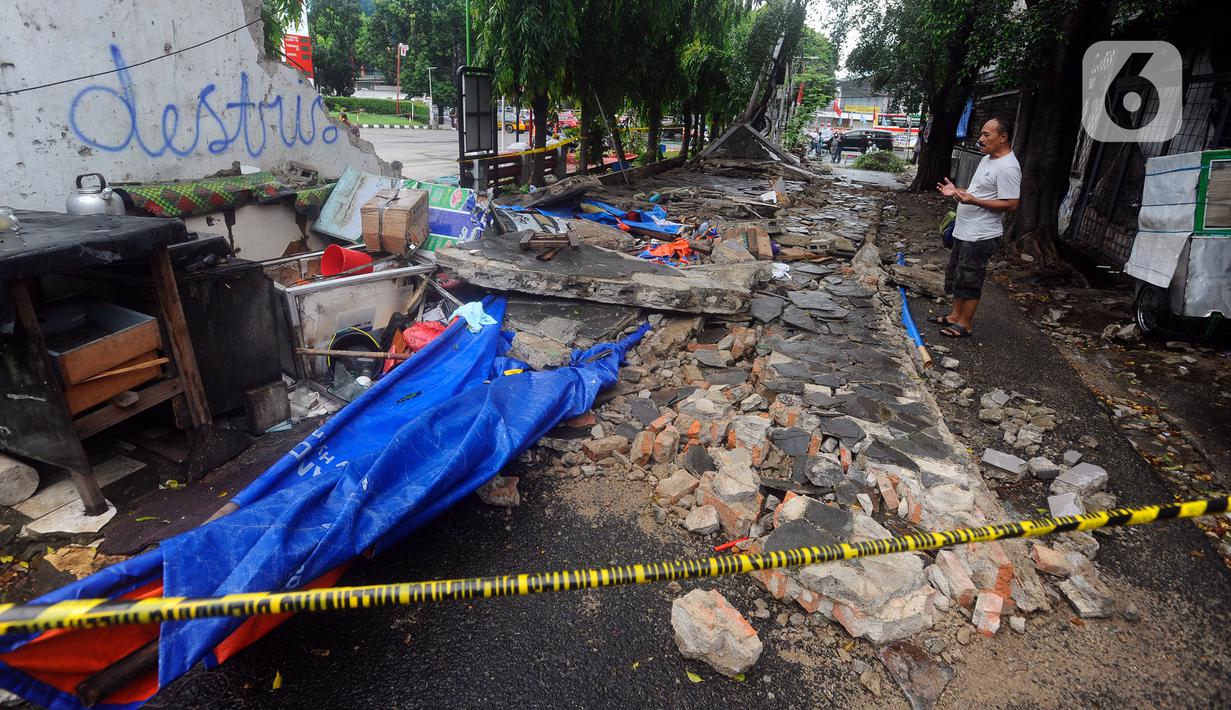 Warga berdoa di lokasi robohnya tembok SPBU di Jalan Tebet Barat Dalam Dua, Jakarta Selatan, Minggu (21/1/2024) siang. Robohnya tembok sepanjang sekitar 50 meter dan tinggi 3 meter saat angin kencang itu menyebabkan tiga warga tewas. (merdeka.com/Arie Basuki)