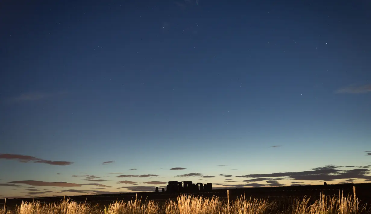 Foto yang diabadikan pada 22 Juli 2020 ini memperlihatkan Komet Neowise di atas monumen Stonehenge di Wiltshire, Inggris. (Xinhua/Tim Ireland)