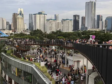 Warga mengisi libur Tahun Baru dengan menikmati pemandangan Kota Jakarta dari Skywalk Senayan Park, Sabtu (1/1/2022). Skywalk Senayan Park kini menjadi salah satu tempat wisata pilihan warga Jakarta lantaran pemandangannya yang instagramable. (Liputan6.com/Johan Tallo)