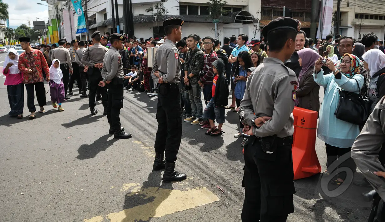 Petugas kepolisian berjaga di depan warga yang ingin melihat Para kepala Negara dan delegasi dari Asia dan Afrika mengikuti 'Historical Walk' dalam Peringatan KAA ke-60, di Jalan Asia Afrika, Bandung, Jumat (24/4/2015). (Liputan6.com/Faizal Fanani)