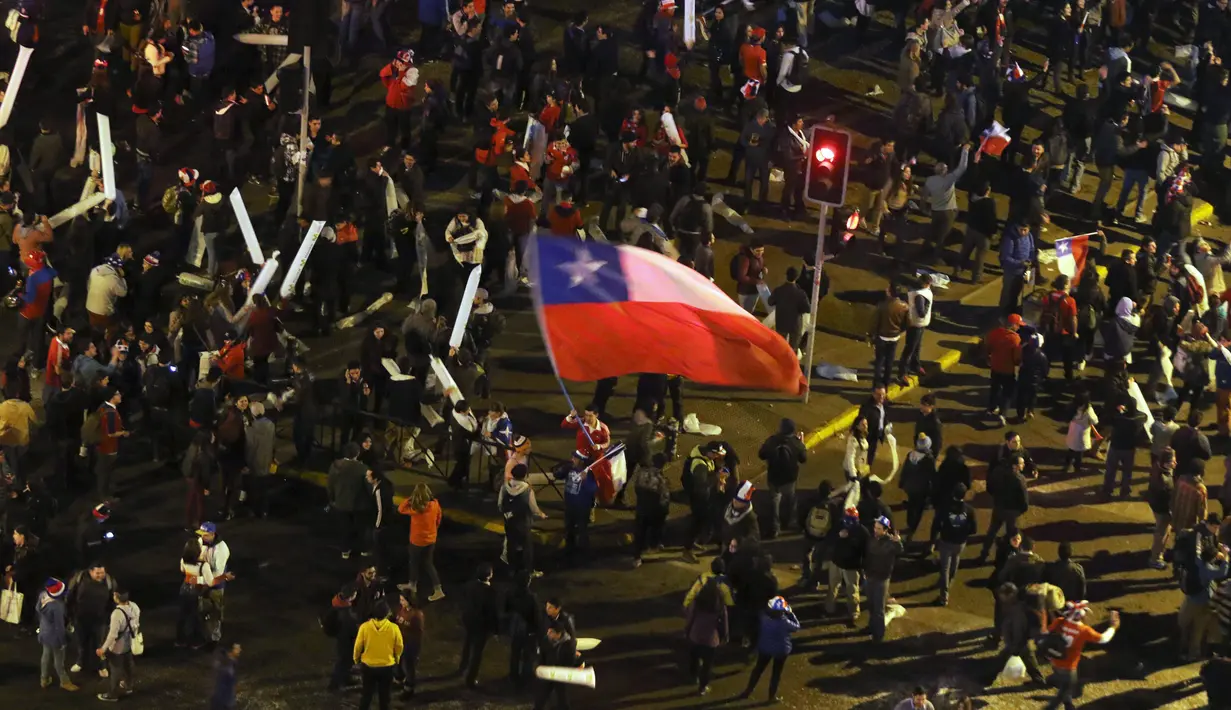 Seorang Suporter membawa bendera nasional Chile di kerumunan merayakan kemenangan Chile atas Uruguay di Copa America 2015 di Santiago, Chile, (25/6/2015). Chile melaju ke semifinal usai mengalahkan Uruguay 1-0. (REUTERS/Catherine Allen)