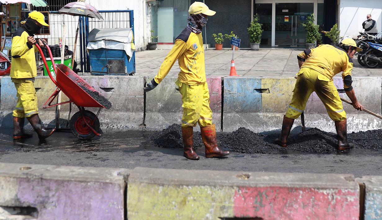 Petugas Bina Marga Pasar Minggu menambal jalan yang rusak di Jalan Raya Ragunan, Jakarta, Senin (22/4). Petugas mengaku bahwa keberadaan beton pembatas jalan justru membuat jalan di kawasan tersebut selalu rusak setiap hujan deras karena menimbulkan genangan air. (Liputan6.com/Immanuel Antonius)