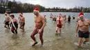 Puluhan anggota klub renang es "Berliner Seehunde" merayakan Natal dengan berenang di danau Orankesee, Berlin (25/12/2014). (REUTERS/Fabrizio Bensch)