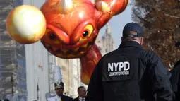 Petugas Kepolisian Kota New York mengawasi mengawasi Parade Thanksgiving Day di New York City (26/11/2015). Beragam balon raksaksa yang dibuat seperti tokoh animasi menjadi suguhan utama dalam perayaan tersebut. (AFP Photo/Timothy A. Clary)