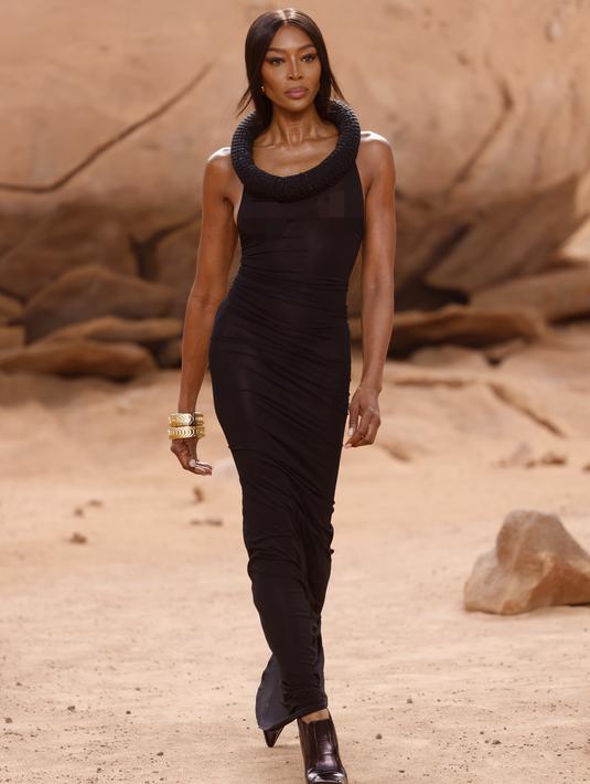 <p>Naomi Campbell berjalan di runway Off-White Fall/Winter 2023-2024 pada acara Paris Fashion Week, Prancis, Kamis, 2 Maret 2023. Gaun Naomi menampilkan bentuk tubuh yang pas dengan garis leher berhiaskan permata yang kebesaran, dipasangkan dengan sepatu bot bertumit dan gelang emas tebal. (Vianney Le Caer/Invision/AP)</p>