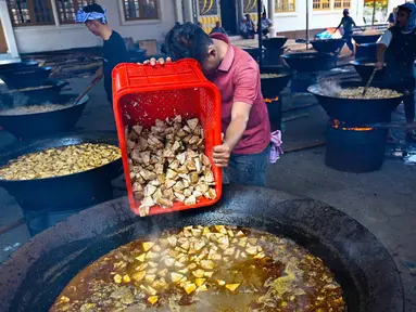 Para pria memasak hidangan kari tradisional yang disebut 'kuah beulangong' untuk dibagikan saat berbuka puasa, sekaligus memperingati turunnya Al-Quran selama bulan suci Ramadan, di Banda Aceh pada Sabtu 7 Maret 2026. Kuah Beulangong merupakan kuliner legendaris khas Aceh yang menjadi tradisi penting selama bulan Ramadan, terutama di wilayah Aceh Besar dan Banda Aceh. (CHAIDEER MAHYUDDIN/AFP)