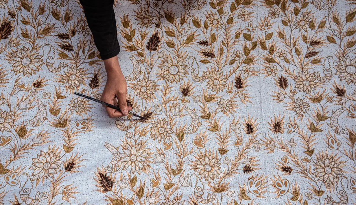 Seorang pekerja mewarnai kain batik saat proses pembuatan di Sidoarjo, Jawa Timur, Sabtu (1/10/2022). Indonesia akan memperingati Hari Batik Nasional pada 2 Oktober. (JUNI KRISWANTO/AFP)