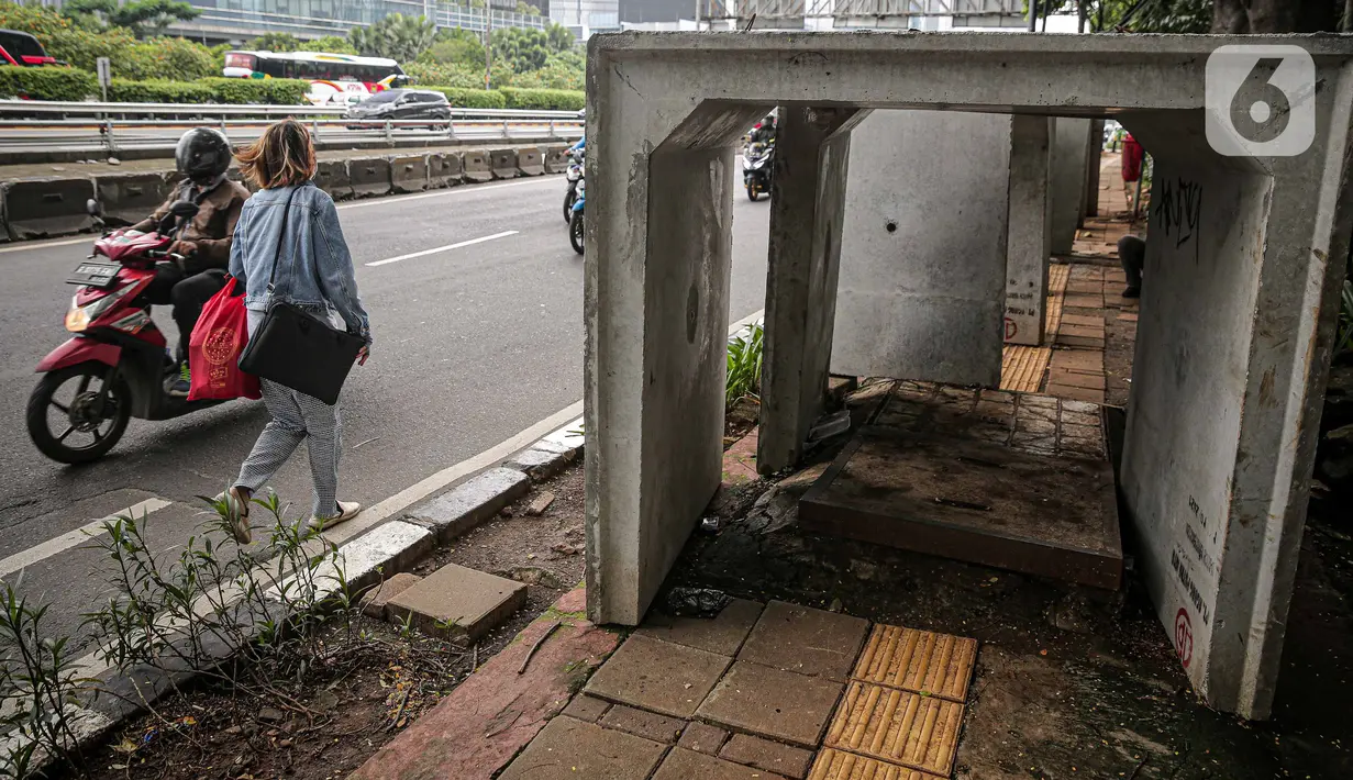 Pejalan kaki melintas di samping beton saluaran air yang berada di jalur pedestrian kawasan Gatot Subroto, Jakarta, Selasa (21/12/2021). Selain mengganggu kenyamanan, keberadaan beton saluran air tersebut juga dapat membahayakan pejalan kaki yang melintas. (Liputan6.com/Faizal Fanani)