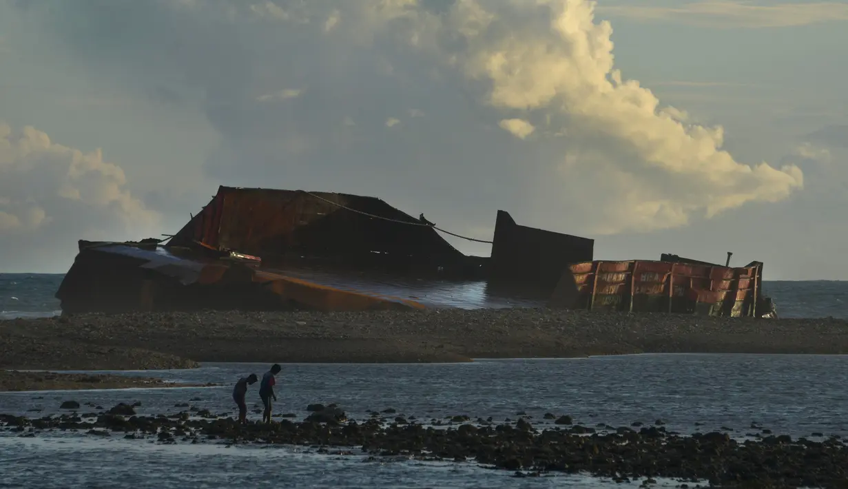Pengunjung berjalan di pantai Lhoknga yang tercemar tumpahan batu bara dari kapal tongkang di Aceh, Rabu (1/8). Sekitar 7.000 ton batu bara tumpah dari kapal tongkang yang kandas dihantam gelombang sehingga merusak terumbu karang. (AFP/CHAIDEER MAHYUDDIN)