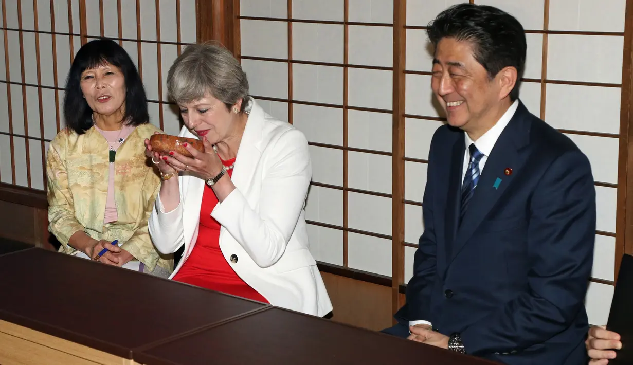 Perdana Menteri Inggris Theresa May (tengah) saat mengikuti upacara minum teh bersama Perdana Menteri Jepang Shinzo Abe di Kyoto, Jepang (30/8). (Hirofumi Yamamoto/Japan Pool Photo via AP)