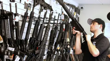 Penjaga toko Ryan Martinez  saat merapikan barang dagangannya di toko senjata "Ready Gunner", Utah, AS, (21/6). Maraknya kasus penembakan yang baru saja terjadi di Orlando, pemerintah AS akan menerapkan pengendalian senjata api. (REUTERS / George Frey)