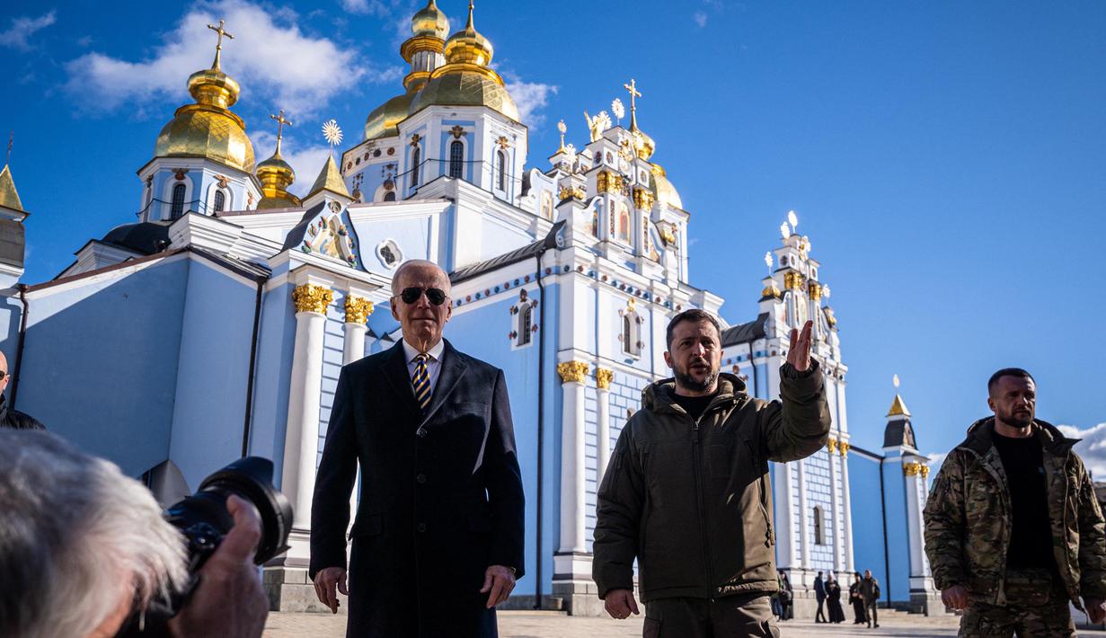 Presiden AS Joe Biden (kiri) berjalan di samping Presiden Ukraina Volodymyr Zelensky di depan Katedral Kubah Emas Santo Mikhael ketika ia tiba untuk kunjungan di Kyiv, Ukraina pada 20 Februari 2023. Presiden AS Joe Biden melakukan kunjungan mendadak ke Kyiv menjelang peringatan satu tahun invasi Rusia ke Ukraina. Biden bertemu dengan Presiden Ukraina Volodymyr Zelensky di ibu kota Ukraina dalam kunjungan pertamanya ke negara itu sejak dimulainya konflik. (Dimitar DILKOFF/AFP)