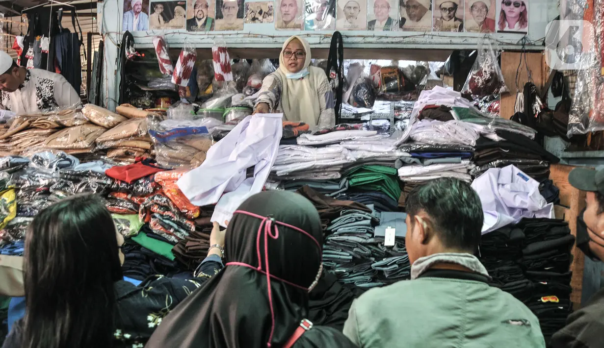 Pedagang melayani pembeli seragam sekolah di Pasar Mester Jatinegara, Jakarta Timur, Senin (3/1/2022). Salah satu pedagang mengungkapkan penjualan seragam sekolah mengalami peningkatan 50 persen seiring pemberlakuan PTM di Jakarta yang kembali digelar 100 persen. (merdeka.com/Iqbal S. Nugroho)