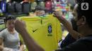 Pembeli melihat jersey Brasil tim peserta Piala Dunia 2022 Qatar di salah satu kios di Blok B Pasar Tanah Abang, Jakarta, Jumat (18/11/2022). Jersey sejumlah tim nasional favorit peserta Piala Dunia 2022 Qatar seperti Belanda, Brasil, Jerman, serta Argentina banyak diburu pembeli. (Liputan6.com/Faizal Fanani)