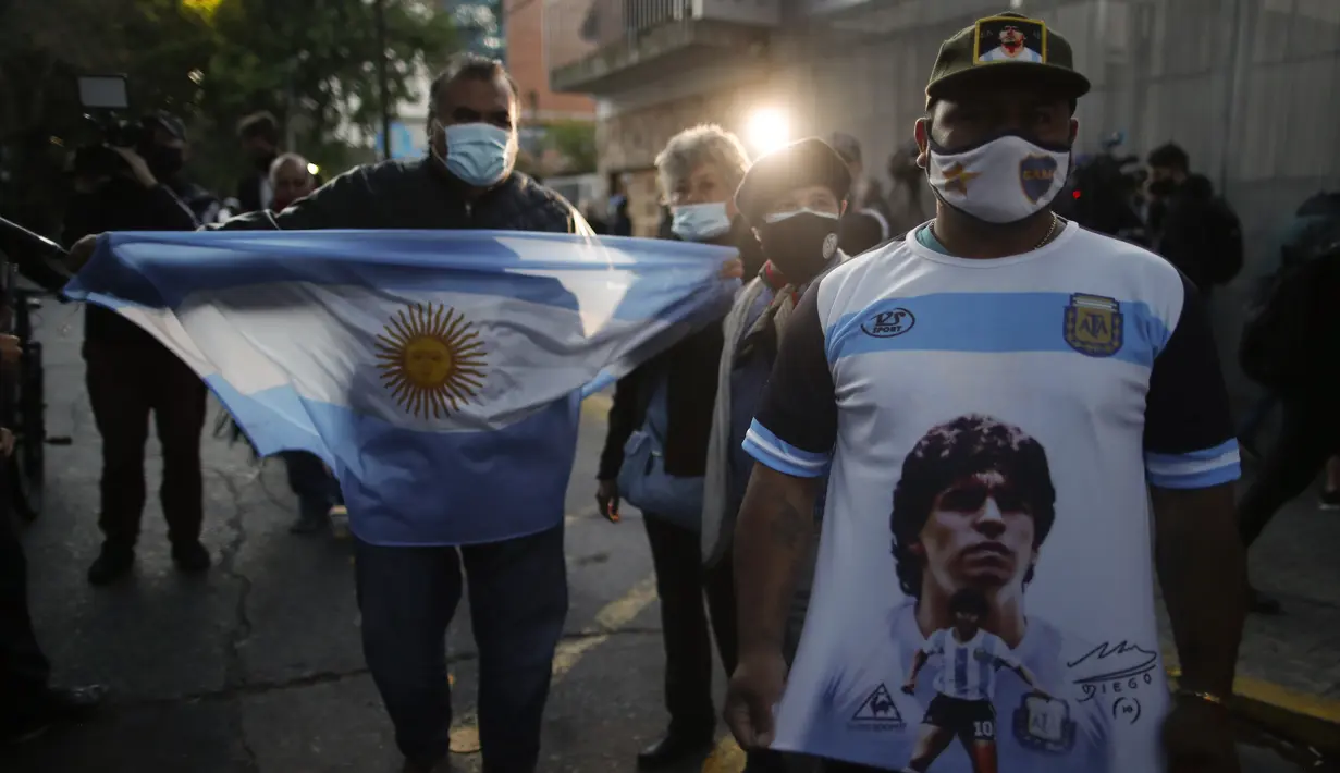 Penggemar sepak bola berkumpul di luar Clinica Olivos, tempat mantan bintang sepak bola Argentina Diego Maradona akan menjalani operasi, di Buenos Aires, Selasa (3/11/2020). Diego Maradona menjalani operasi hematoma subdural atau pembekuan darah di otak. (AP Photo/Natacha Pisarenko)