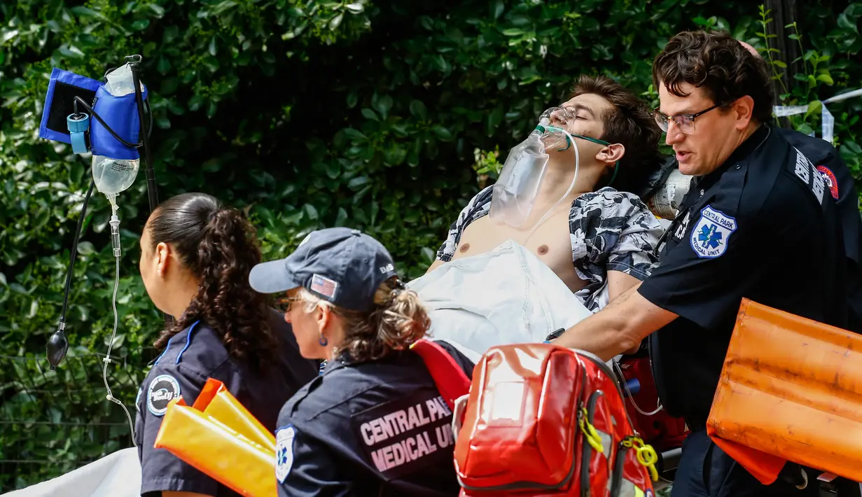Petugas mengevakuasi seorang pemuda yang terluka parah setelah menjadi korban ledakan di Central Park, New York, Minggu (3/7). Sebagian Central Park pun langsung ditutup sementara personel NYPD melakukan penyelidikan. (Kena Betancur/AFP)