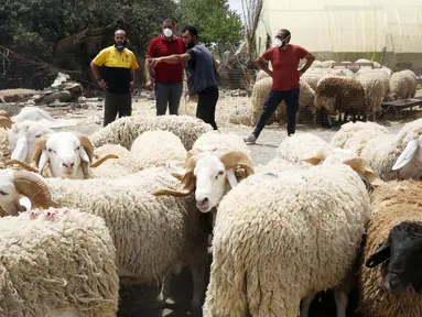 Sejumlah orang terlihat di sebuah kios penjualan domba kurban menjelang Hari Raya Idul Adha di Aljir, Aljazair, Minggu (12/7/2020). (Xinhua)