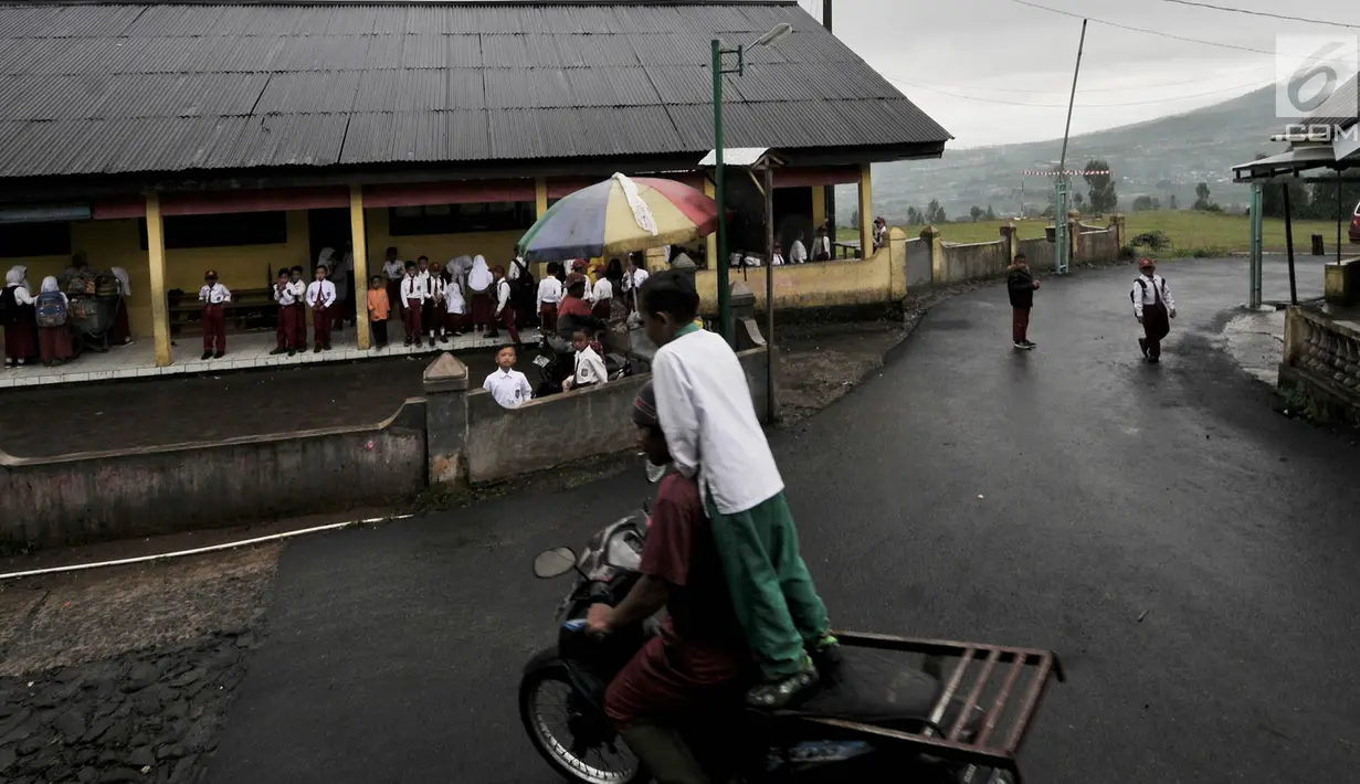 Siswa bermain di halaman sekolah dengan latar belakang pemandangan Gunung Sindoro yang tertutup kabut sebelum dimulainya kegiatan belajar di Gedung Sekolah Dasar (SD) Negeri 2 Bowongso, Kecamatan Kalikajar, Wonosobo, Jawa Tengah (2/4). (merdeka.com/Iqbal S. Nugroho)