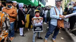 Seorang anak membawa poster wajah Richard Eliezer Pudihang Lumiu usai sidang pembacaan vonis kasus pembunuhan Brigadir Yosua Hutabarat di Pengadilan Negeri Jakarta Selatan, Rabu (15/2/2022). Eliezer merupakan ajudan dari istri Ferdy Sambo yang telah mengabdi sejak 2013. Saat itu, Ferdy Sambo masih menjabat sebagai Kapolres Brebes. Eliezer sendiri, bertugas di Brebes sebagai Satlantas Polres Brebes. (Liputan6.com/Johan Tallo)