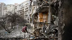 Seorang pria membersihkan puing-puing setelah peluru militer Rusia menghantam di sebuah bangunan tempat tinggal di Koshytsa Street, pinggiran ibukota Ukraina, Kiev (25/2/2022). Pasukan Rusia mencapai pinggiran Kyiv pada hari Jumat (24/2). (AFP/Daniel Leal)