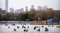 Orang-orang menggunakan kursi yang dimodifikasi untuk meluncur melintasi es dalam kolam saat pekan liburan Tahun Baru Imlek di taman umum selama pekan liburan Tahun Baru Imlek di Beijing, China, Kamis (26/1/2023). (AP Photo/Mark Schiefelbein)