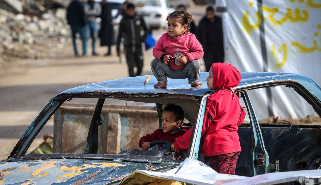 Dan, lebih dari 700.000 anak kehilangan akses ke pendidikan formal selama hampir dua tahun terakhir. Tampak dalam foto, anak-anak bermain di reruntuhan kendaraan yang hancur di kamp pengungsi Palestina Nuseirat di utara Deir al-Balah, Jalur Gaza tengah pada 29 Januari 2026. (EYAD BABA/AFP)