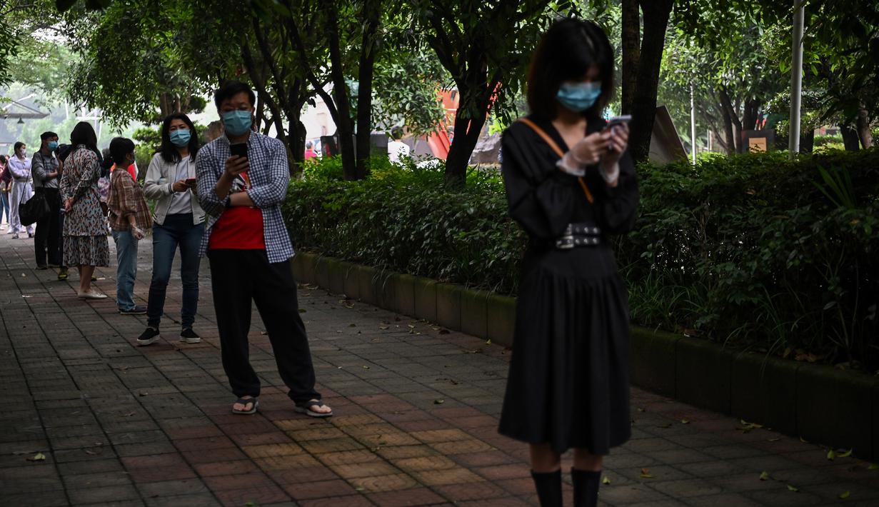 Warga mengenakan masker menunggu dalam barisan untuk tes virus corona di lingkungan di Wuhan, provinsi Hubei, China, Jumat (15/5/2020). Pihak berwenang Kota Wuhan menggelar tes massal terhadap 11 juta warganya untuk mencegah gelombang kedua pandemi Covid-19. (Hector RETAMAL/AFP)