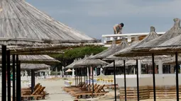 Seorang pekerja memperbaiki atap bar di sebuah pantai di Qerret, dekat kota Kavaja, Albania pada 1 Juni 2020. Rencananya pada 6 Juni mendatang, semua pantai umum akan dibuka untuk wisatawan setelah Albania menerapkan langkah-langkah pelonggaran pencegahan virus corona. (SHKULLAKU / AFP)